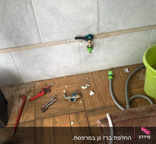 ברז וכלי עבודה על רצפה, דלי ירוק וצינור
